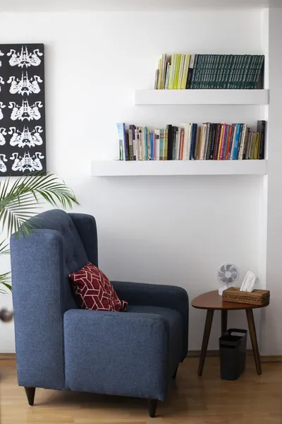 Consultorio con sillón azul frente a libreros
